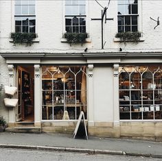 a store front with many windows and plants in the window sill on the sidewalk