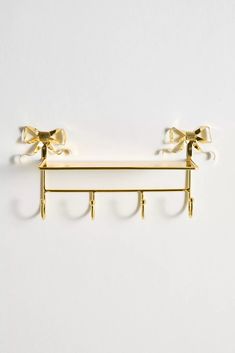 three gold bow hooks on a white wall