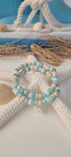 TitiTataStore.etsy.com Always FREE SHIPPING and a FREE GIFT! I Will Ship Within 24 Hours! Description: A Beautiful Set of 2 Coastal Style Ocean Inspired Beachy Bracelets. Materials: Aqua Shell Beads, 6mm Natural Matte Riverstone Beads, 6mm Natural Wood Beads, White Heishi Seashell Beads, and 6mm Rondelle Magnesite Beads.  A coastal Clam Shell charm adorned this Beachy Style set. Every bracelet is handmade using a high-quality elastic stretch cord for durability. Size: Each bracelet is suitable f Cheap Multicolor Beachy Jewelry, Cheap Beaded Bracelets For Summer Beach Party, Cheap Beachy Beaded Bracelets For Beach Party, Cheap Blue Beaded Bracelets For The Beach, Affordable Handmade Beaded Bracelets For Beach Season, Turquoise Hand Wrapped Wrap Bracelet For Beach, Adjustable Coastal Beaded Bracelets For Gift, Adjustable Coastal Beaded Bracelets As Gift, Handmade Wrap Bracelet With Round Beads For Beach