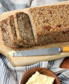 sliced loaf of bread with butter and knife next to it on a wooden cutting board