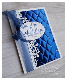 a close up of a greeting card with a ribbon on the front and blue quilted background