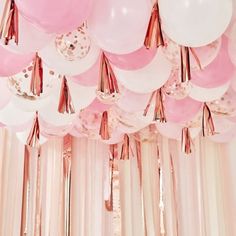 pink and white balloons are hanging from the ceiling