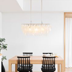 a dining room table with four chairs and a chandelier hanging from the ceiling