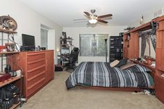 a bedroom with a bed, dressers and ceiling fan