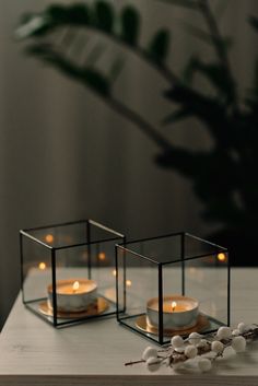 two candles are sitting in glass containers on a table