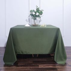 a table with a green cloth on it and flowers in a vase at the top