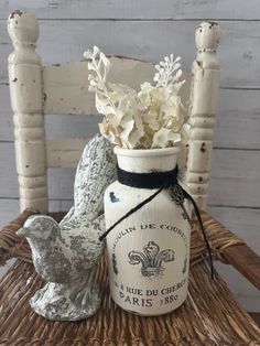 a white vase with flowers in it sitting on a wicker chair