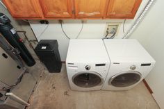 two washers are sitting next to each other in the corner of a room with wooden cabinets