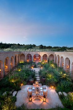 an outdoor dining area is lit up at night with candles on the tables and chairs