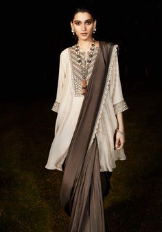 Editor's Note Featuring a charocal grey sari with tarnished silver vintage zardozi embroidery in Aztec and flora inspired artworks. It comes with limestone grey A-line kurta. Fabric: Silk Color: Beige, grey Sleeves: Three Quarter Neckline: Notch Component: Sari and kurta Occasion: Wedding guest Disclaimer: Product colour may slightly vary due to photographic lighting sources Care: Dry Clean Only About the Designer Matsya by Utkarsh Ahuja curated for the princess in disguise, royal humility at th Grey Sari, Limestone Grey, Suit Combinations, Blouse Yoke, Zardozi Embroidery, A Line Kurta, Pakistani Dress, Watches Women, Tarnished Silver