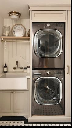 two washers are stacked on top of each other in a kitchen with white cabinets