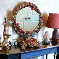 a mirror sitting on top of a blue table next to a lamp and a vase