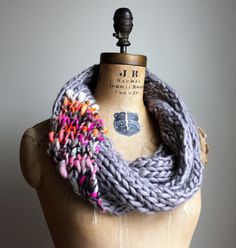 a mannequin wearing a gray knitted scarf with multicolored flowers on it