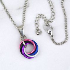 view size guide Small Swirl Pendant in coral, white, violet, black and blue to match the Genderfluid Pride flag.💗 very lightweight - comfortable and easy to wear/stack🤍 adjustable chain length up to 2" longer than the length you select from the drop-down menu💜 approximately 1" long (including bail) and 0.5" wide🖤 Aluminum links with stainless steel chain, pendant bail and lobster claw clasp Swirl Necklace, Genderfluid Pride, White Violet, Pendant Bail, Mini Love, Pendant Bails, Pride Flag, Chain Pendant, Pride Flags