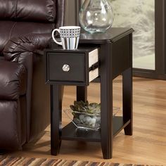 a small end table with a coffee cup on it next to a reclining chair