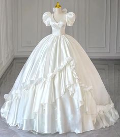 a white wedding dress with ruffled skirt and gold tiara on display in a room