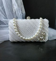 This exquisite White Pearl Evening Clutch Bag with Silver Hardware is the perfect accessory for any formal event. Whether you're a bride looking for the ultimate finishing touch or a bridesmaid wanting to add a touch of elegance to your ensemble, this stunning handbag is sure to make a statement. The lustrous white pearls and sleek silver hardware combine to create a timeless and sophisticated piece that will elevate your look. Add this versatile purse to your collection and shine bright at your Elegant White Handheld Evening Bag, Elegant Handheld Evening Bag For Wedding, Elegant Pearl White Bag As A Gift, Elegant Pearl White Evening Bag For Formal Occasions, Elegant Pearl White Rectangular Evening Bag, Elegant Formal Pearl White Bags, Elegant White Bags For Formal Occasions, Elegant White Formal Bags, Elegant White Formal Bag