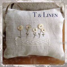 a white pillow with buttons on it and the words t & linen written in blue