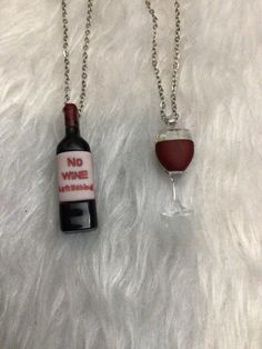 two wine bottles are sitting on a white fur covered surface, one is filled with red liquid and the other has a silver chain