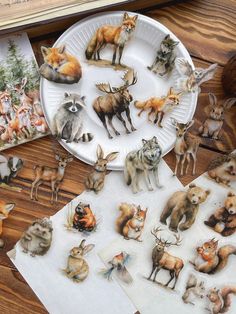 a paper plate filled with lots of different animals on top of a wooden table next to pictures