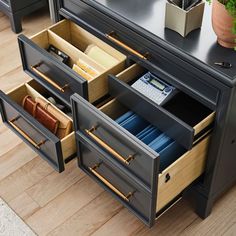 an office desk with two drawers and a calculator on the bottom drawer that is open