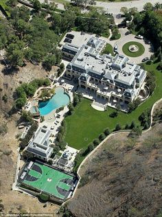 an aerial view of a large mansion with a swimming pool and tennis court in the foreground