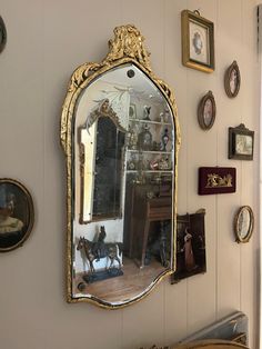 an ornately decorated mirror hangs on the wall in a room with many framed pictures