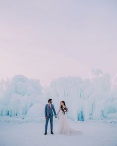 a bride and groom hold hands in front of ice formations at their winter elopement