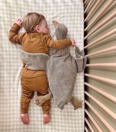 a baby sleeping in a crib with a stuffed animal on it's back