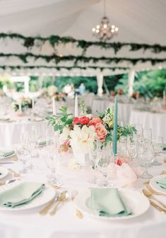 the table is set with white linens and floral centerpieces, along with silverware