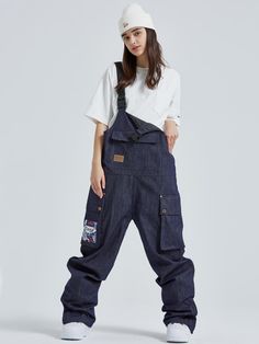 a woman in overalls and white hat standing with her hands behind her back to the camera