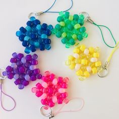 four different colored beads are on a white surface and one is holding a pair of scissors