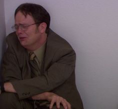 a man sitting on the floor with his arms crossed and looking off into the distance