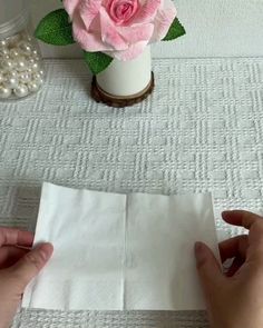 someone is making a flower out of tissue paper on a table with pearls and beads