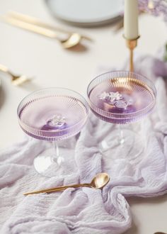 two wine glasses sitting on top of a table next to a candle and some silverware