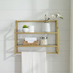 a bathroom shelf with towels, soaps and other items on it in front of a white wall