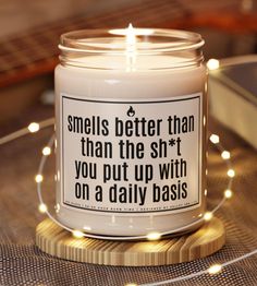 a candle that is sitting on a table with some string lights around it and the words smells better than the shr you put up with on a daily basis