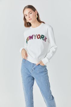 Add a touch of Big Apple flair to your wardrobe with our New York Embellished Sweatshirt. Made with soft, cozy material and a relaxed fit, this sweatshirt is perfect for all-day comfort. The round neckline and long sleeves add a classic touch, while the New York embellishment brings a stylish twist. Versatile enough to wear with anything, this sweatshirt is sure to become your new go-to. Upgrade your hoodie and sweatshirt collection with our must-have New York Embellished Sweatshirt. Sweatshirt Fall Sweater With Embroidered Text, Trendy White Sweatshirt With Embroidered Text, White Trendy Sweatshirt With Embroidered Text, Sweatshirt Collection, Embellished Sweatshirts, Knit Bottom, Tweed Dress, Blazer And Shorts, Big Apple