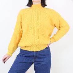 Item Description  Super cute knit pullover sweater! Love the marigold yellow color, and the details throughout; the ribbed mockneck, the unique aran style cable knit design on the front, and the heavy high quality feel of the all-cotton material. Love the comfy fit and the versatility of a sweater like this! It is in excellent condition with no flaws to note.  Item Specifics  Brand - Across America  Material - 100% cotton Color - Marigold yellow Measurements  Shoulder to Hem - 24 in.  Sleeve Len Retro Chunky Knit Sweater For Fall, Retro Chunky Knit Fall Sweater, Retro Cable Knit Sweater For Fall, Winter Yellow Cable Knit Sweater, Casual Yellow Cable Knit Sweater, Retro Long Sleeve Cable Knit Sweater, Yellow Turtleneck Sweater For Fall, Retro Knit Turtleneck Sweater, Retro Turtleneck Knit Sweater