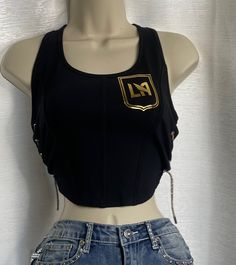 LAFC Corset Top with side cuts and gold rhinestone lace. Please note estimated time to ship these items is 7-10 business days as they are made to order. If you need it right away please send us a message and we will try our best to accommodate your request. Crystal Corset Shirt, Corset Over Band Tee, Black Embellished Sleeveless Corset, Corset T-shirts & Tank Tops, Gothic Sleeveless Corset With Lace Trim, Side Cuts, Gold Rhinestone, Corset Top, Womens Clothing Tops