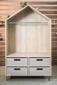 a wooden shelf with two drawers and an open door on the top, in front of a wood wall