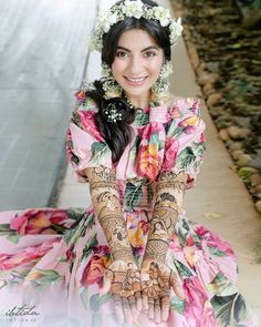 a woman with henna on her hands and flowers in her hair is smiling at the camera