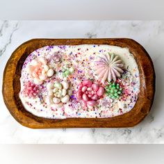 a wooden tray filled with lots of different types of candies and sprinkles