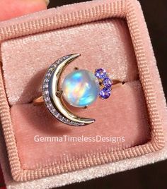 This new galaxy design is a gorgeous natural diamond, moonstone and tanzanite ring, it is perfect for an engagement ring or just a beautiful gift to someone special. The ring is made with 14K solid yellow gold, features a high quality cabochon moonstone (2.00ct, 8mm), side diamonds (approx 0.15ct total weight, Si clarity), natural tanzanites ( 0.12ct, vs clarity). Ring is in size 8.   **All our products will come with a certificate of authenticity provided by The Valuation Centre of Australia wh Celestial 14k Gold Moonstone Ring For Gift, Celestial 14k Gold Moonstone Ring As Gift, Celestial Style 14k Gold Moonstone Ring As Gift, Celestial Moonstone Ring In 14k Gold As Gift, Celestial Opal Ring As Gift, Moonstone Multi-stone Opal Ring As Gift, Multi-stone Moonstone Opal Ring For Gifts, Unique Moonstone Ring As A Gift, Celestial Style Opal Gemstone Ring For Gifts