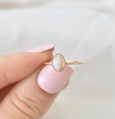 a woman's hand holding a ring with a pearl on it