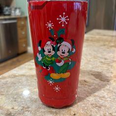 a red cup with mickey and minnie mouses on it sitting on top of a counter