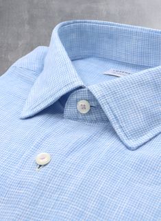 Inspired by the effortless style worn in Portofino, the Alexander in Light Blue Gingham Linen is a must-have of any wardrobe. Crafted of super soft linen fabric, it exudes effortless style when worn untucked. The pale purple stitching on the top collar button and cuffs adds a polished finishing touch. Worn under a suit and with a tie, the shirt exudes casual ease. The Alexander is the trimmest of all our fits, calibrated to accentuate a lean, athletic body type. • Trimmest Fit • 100% Linen • Spr Classic Plaid Linen Shirt, Blue Linen Shirt With Placket, Spring Plaid Linen Shirt, Fitted Blue Linen Shirt, Light Blue Linen Button-up Shirt, Blue Linen Tops For Business Casual, Classic Blue Linen Shirt, Blue Linen Shirt For Daywear, Spring Gingham Shirt With Spread Collar