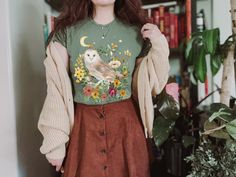 This is the Unisex-Style Barn Owl Tee. It is a super cool, heavy cotton tee with watercolor owl, mushroom, and botanical illustrations arranged in a cute collage. This cute, whimsical cottagecore tee is about to be your fave! This classic T is made with cotton, sometimes polyester (depending on the color) and has no uncomfortable side seams. This design is an original, created by Jillian Anderson @ A Living Whimsy. She uses digital graphic design elements and collage and optimizes each image or Storybook Outfits, Owl Mushroom, Jillian Anderson, Cottagecore Shorts, Owl Outfit, Fairycore Shirt, Cottage Core Shirt, Cute Collage, Whimsical Cottagecore