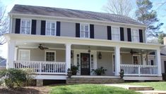 a white two story house with black shutters on the front porch and stairs leading up to it