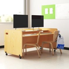 two computer monitors sitting on top of a wooden desk next to a chair in front of a window